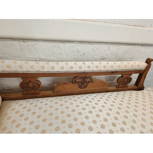 15 - A carved oak chaise longue with cream upholstery. 75cm x 170cm x 63cm.