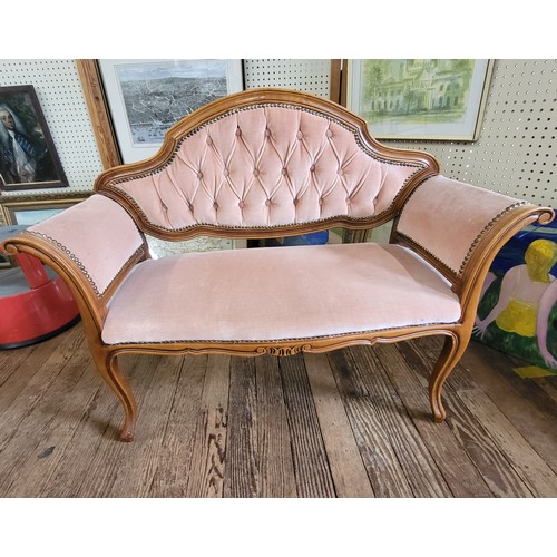 23 - A vintage pink upholstered button back settee. 85cm x 110cm x 43cm.