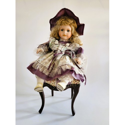 192 - A Leonardo collection bisque headed doll on a reproduction Edwardian balloon back chair (2)