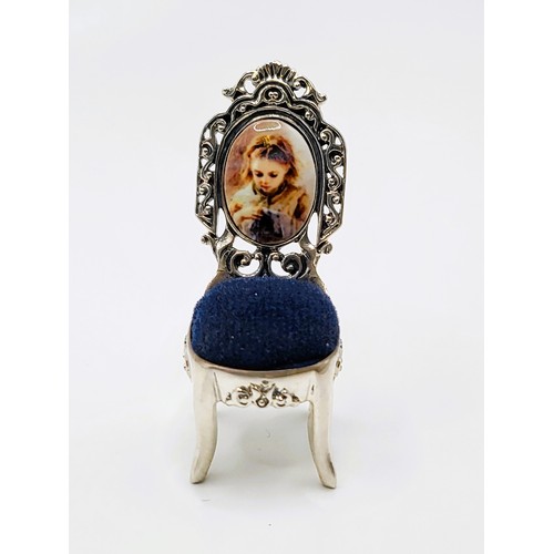 275 - A silver pin cushion in the form of a chair with a portrait of a young girl sewing on the back. Stam... 