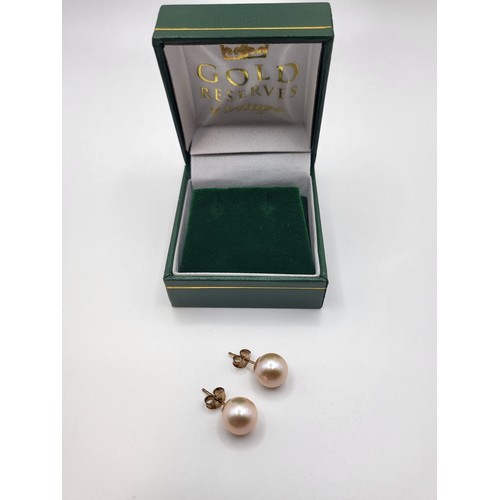 329 - A pair of 9ct yellow gold pink cultured 9mm pearl stud earrings, boxed. 2.4gms.