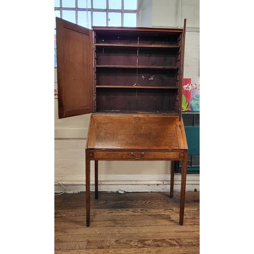 5 - An oak bookcase on bureau. Two doors cupboard with three shelves over a fold down writing desk with ... 