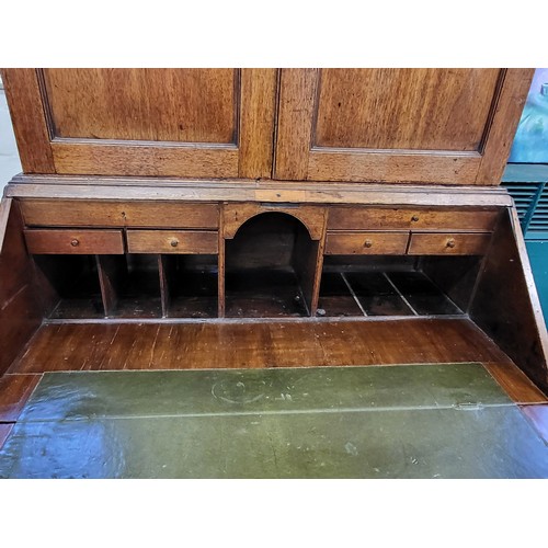 5 - An oak bookcase on bureau. Two doors cupboard with three shelves over a fold down writing desk with ... 