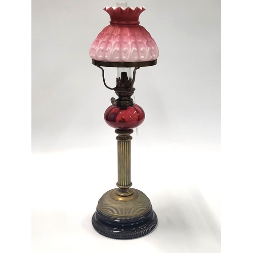 202 - An oil lamp with chimney and pink overlay glass shade, 52cm.