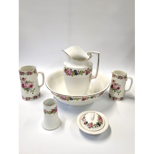 136 - A Burslem jug, basin, lidded soap dish and brush holder, two other jugs with roses pattern.