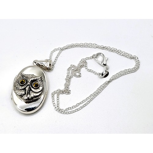 271 - A silver photo locket stamped 925, with embossed owl with glass eyes on a 40cm silver coloured chain... 