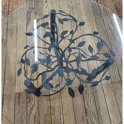 22 - A glass top and iron stand coffee table decorated with vines. 46cm x 81cm diameter.