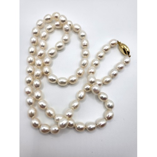 280 - A matinee length white cultured ovoid pearls (7-9mm) with a 9ct yellow gold oval clasp. 51gms.