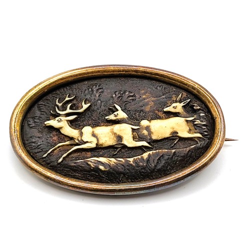 361 - An oval shaped gold brooch depicting a running stag and two doe in carved antler. 10.3gms 3cm x 4.5c... 