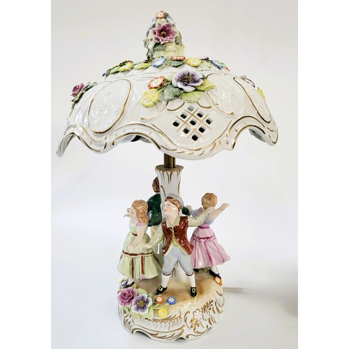 210 - A porcelain lamp base with four dancing figures of children and porcelain shade with encrusted flowe... 