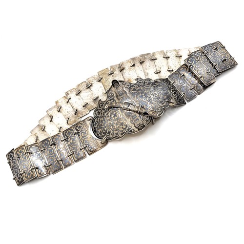 283 - An Eastern European ornate silver belt with dagger locking mechanism on the buckle, with safety chai... 