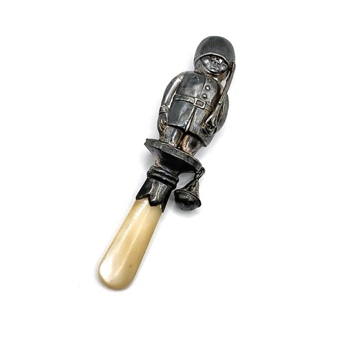 292 - A silver baby's rattle in the shape of a Coldstream Guard in uniform with a mother of pearl handle. ... 