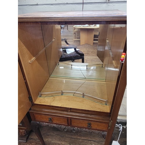 27 - A two-door cocktail mirror-back cabinet (with broken glass shelf),  over two short drawers supported... 