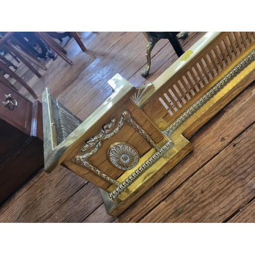 25 - A brass fire dog W:73cm and brass fender W:133cm.