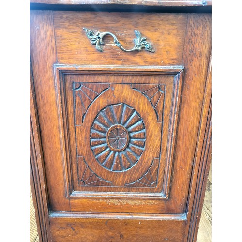 12 - An oak coal purdonium with a raised top on turned supports, fall front with brass handle and carved ... 