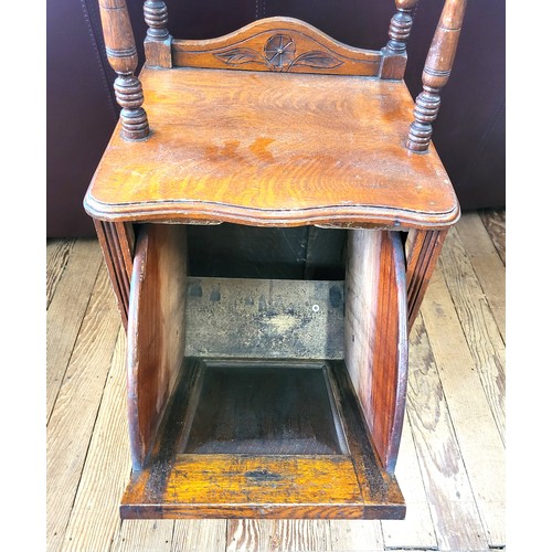 12 - An oak coal purdonium with a raised top on turned supports, fall front with brass handle and carved ... 