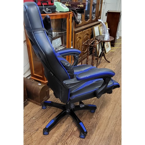28 - A black and blue gaming chair with pull out rest for legs and adjustable lumbar and head support.