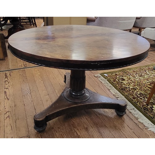69 - A circular dining tilt table with a burr elm top (some damage) on a carved pedestal and tripod legs.... 