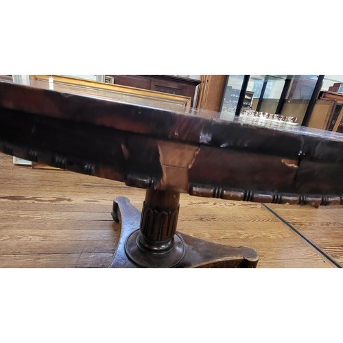 69 - A circular dining tilt table with a burr elm top (some damage) on a carved pedestal and tripod legs.... 