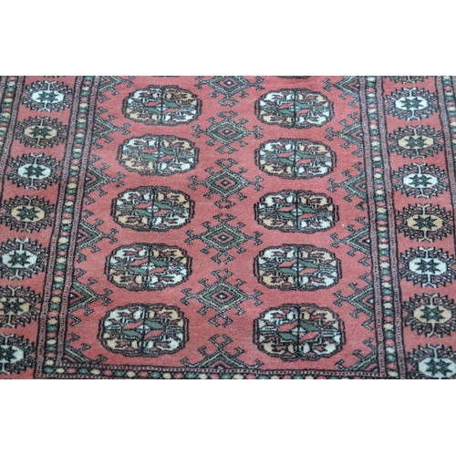 29 - Pakistan runner of Bokhara design with two rows of gols on a pink ground, 10ft x 2ft 10ins approxima... 