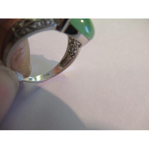 719 - 18ct White gold oval jade set ring with diamond set shoulders