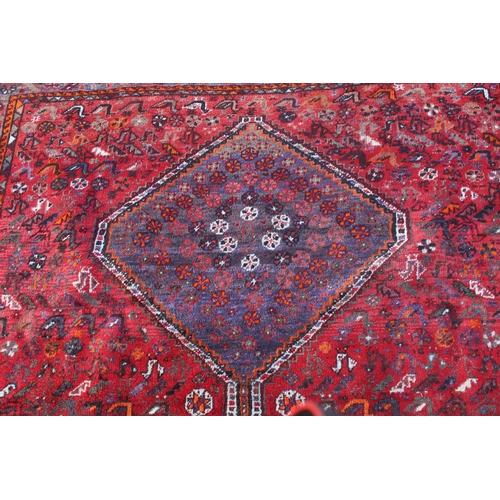 19 - Shiraz carpet with a triple pole medallion and all-over stylised design on a red ground with multipl... 