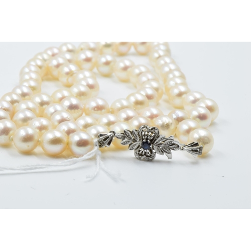 927 - Single row uniform cultured pearl necklace with sapphire set white metal clasp, 26ins long