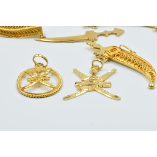 944 - Three Omani yellow metal dagger brooches together with two similar pendants, 22.5g