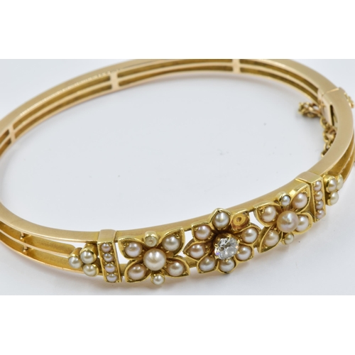 899 - 15ct Gold bangle of pierced floral design set with a single diamond and multiple split pearls (one s... 