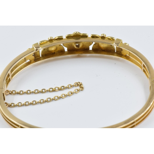 899 - 15ct Gold bangle of pierced floral design set with a single diamond and multiple split pearls (one s... 