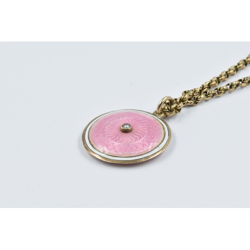 904 - Circular pink enamel pendant locket suspended from a 9ct gold chain the chain 4.8g