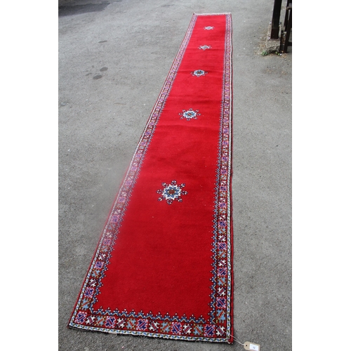 12 - North African woollen runner on wine ground, 21ins x 2ft 8ins approximately