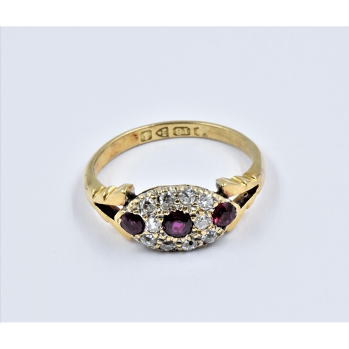 852 - 18ct Gold ruby and diamond dress ring, the oval head with three small rubies surrounded by ten small... 