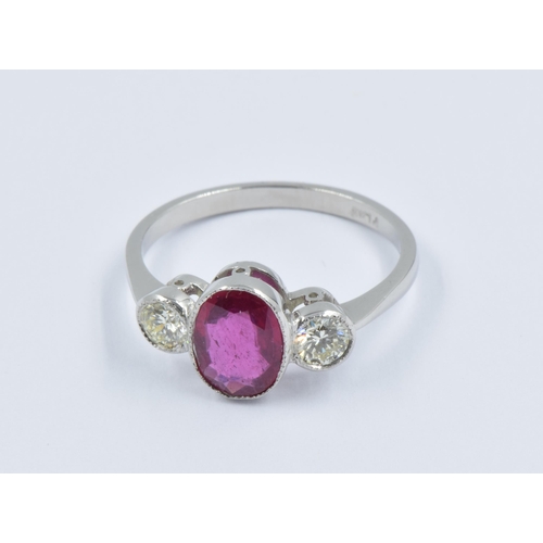 900 - Platinum ring set central oval ruby flanked by two circular cut diamonds, size N