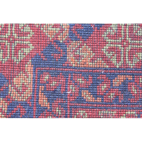 10 - Afghan carpet with an all-over hooked floral medallion design on a madder ground with multiple borde... 