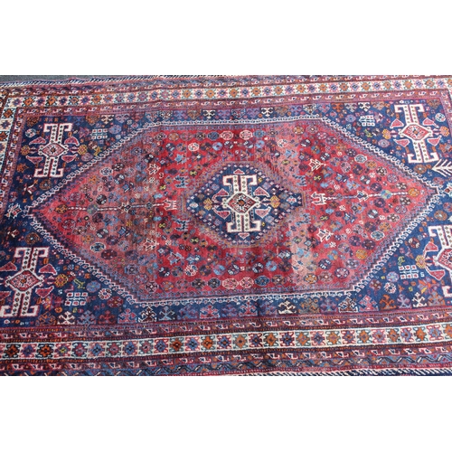 11 - Large Shiraz rug with a medallion and all-over stylised design on a red ground with blue corner desi... 