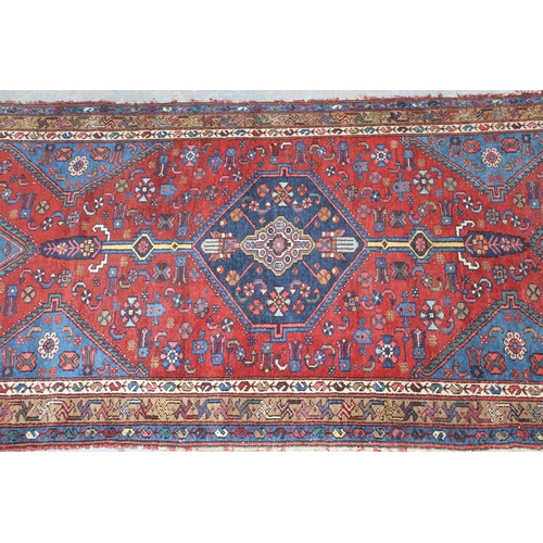 12 - Small Kurdish rug with a lobed medallion and all-over stylised floral design on a brick red field wi... 