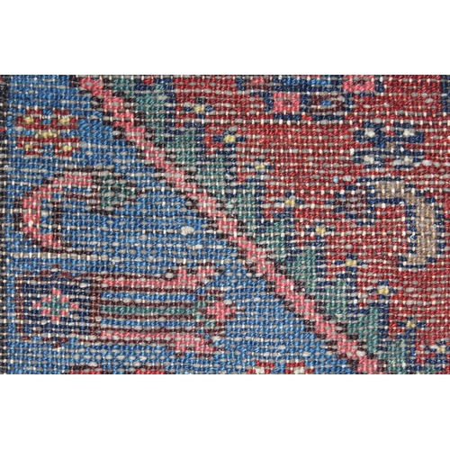 12 - Small Kurdish rug with a lobed medallion and all-over stylised floral design on a brick red field wi... 