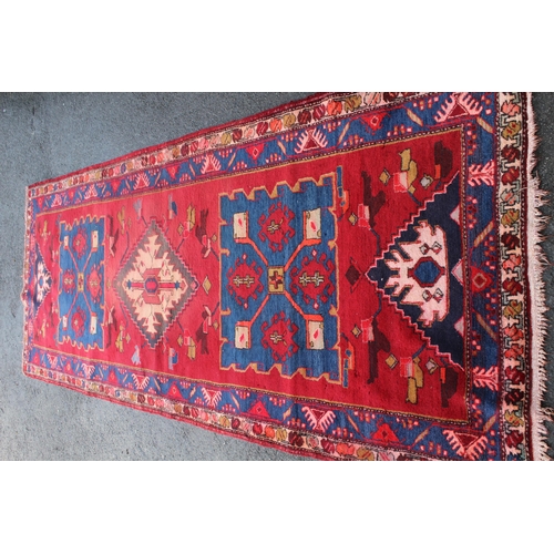 16 - Kurdish runner with a triple medallion design on a wine ground with borders, 10ft 6ins x 4ft 2ins