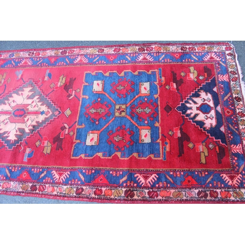 16 - Kurdish runner with a triple medallion design on a wine ground with borders, 10ft 6ins x 4ft 2ins