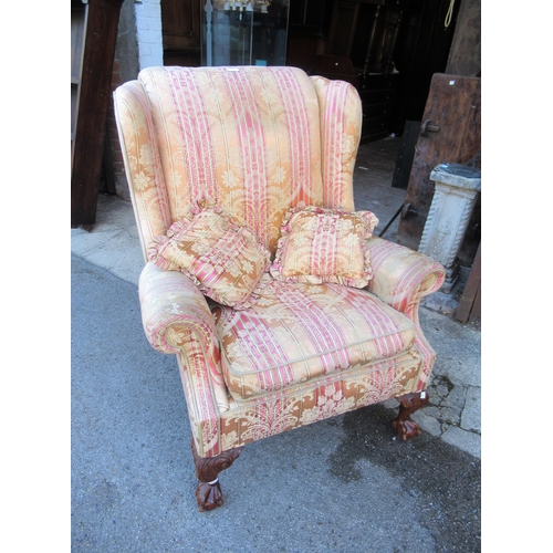 2014C - Floral upholstered wing back armchair, raised on carved cabriole claw and ball front supports