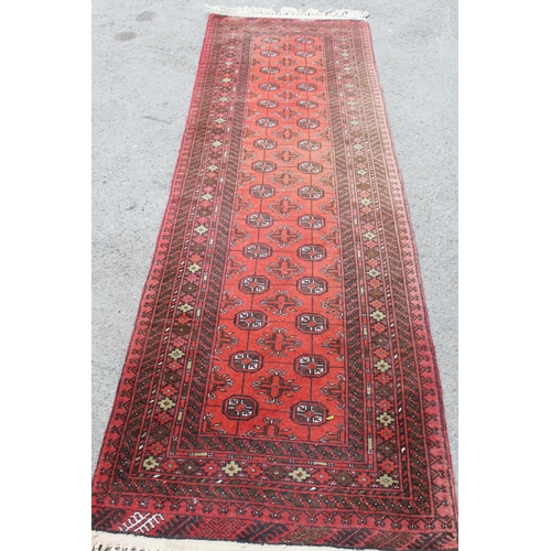 33 - Afghan runner with repeating gol design on a red ground with borders, 9ft 8ins x 2ft 10ins approxima... 