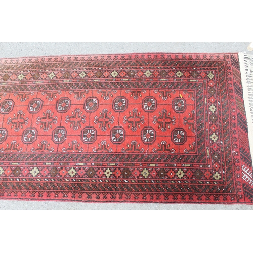 33 - Afghan runner with repeating gol design on a red ground with borders, 9ft 8ins x 2ft 10ins approxima... 