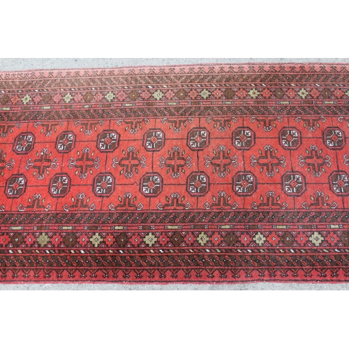 33 - Afghan runner with repeating gol design on a red ground with borders, 9ft 8ins x 2ft 10ins approxima... 