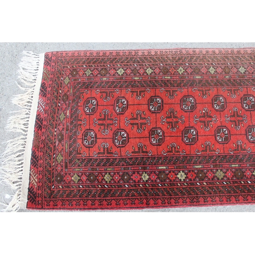 33 - Afghan runner with repeating gol design on a red ground with borders, 9ft 8ins x 2ft 10ins approxima... 