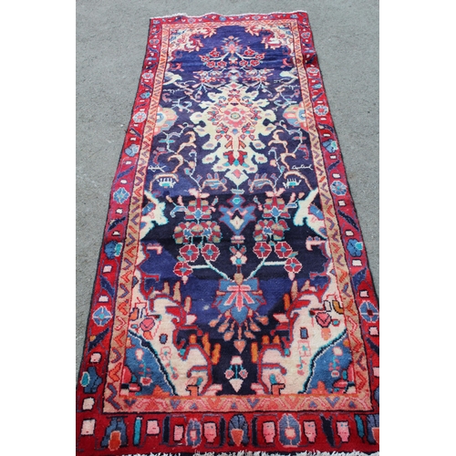 34 - Sarouk runner with a medallion and floral design on a blue ground with borders, 8ft 2ins x 2ft 10ins... 