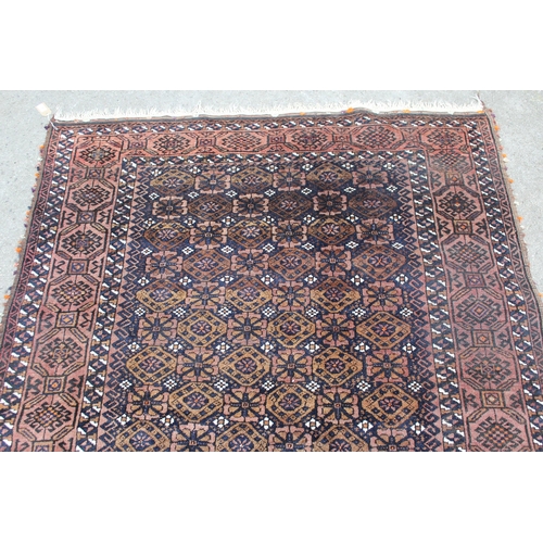 43 - Belouch rug with an all-over flowerhead design in shades of beige and dark blue within a hooked meda... 