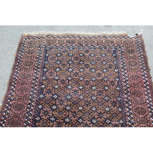 43 - Belouch rug with an all-over flowerhead design in shades of beige and dark blue within a hooked meda... 