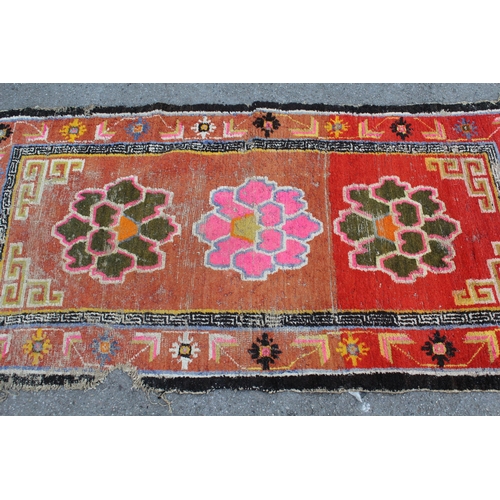 45 - Small Tibetan rug with a triple medallion and polychrome design, 5ft 6ins x 2ft 10ins approximately ... 