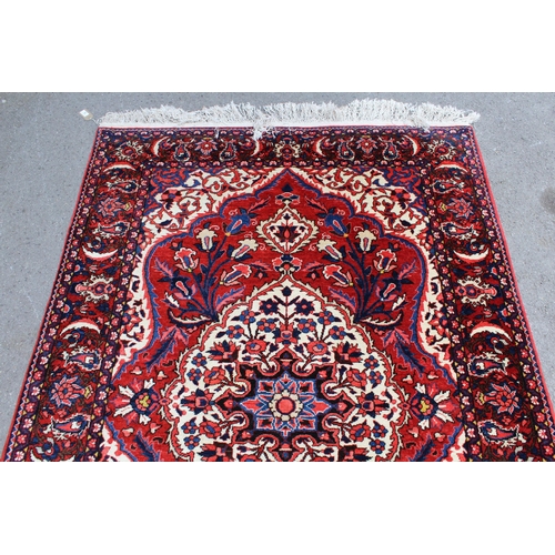 52 - Bakhtiari rug with a medallion and all-over floral design on a red ground with ivory corner designs ... 